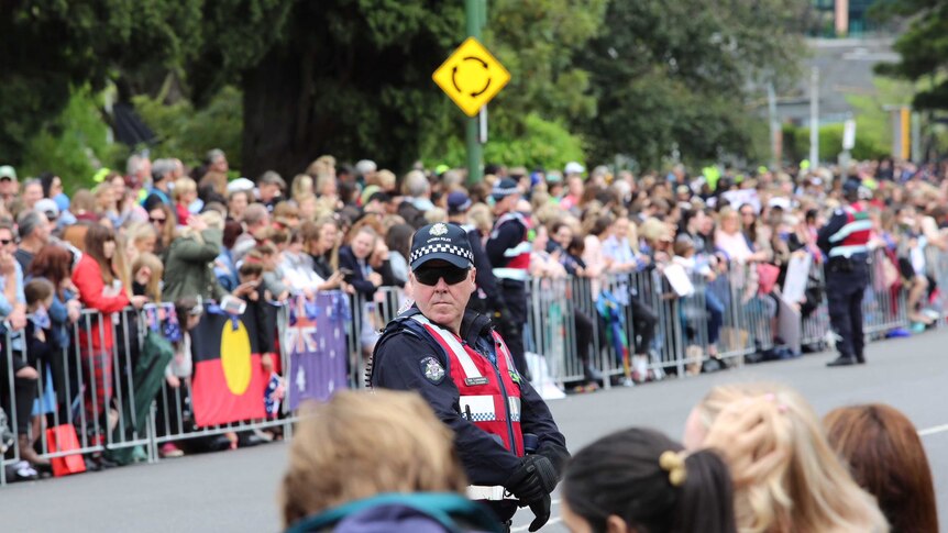 Crowds behind barrier, with policeman in foreground