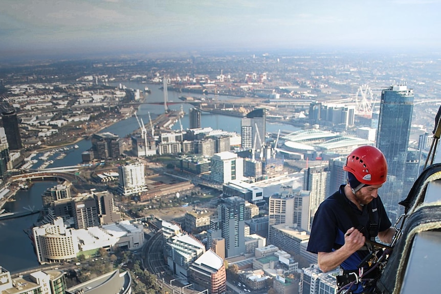 A man starts to abseil down the side of a building