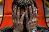 A miner holds his heads in his hands after being affected with toxic gas while searching for co-workers.