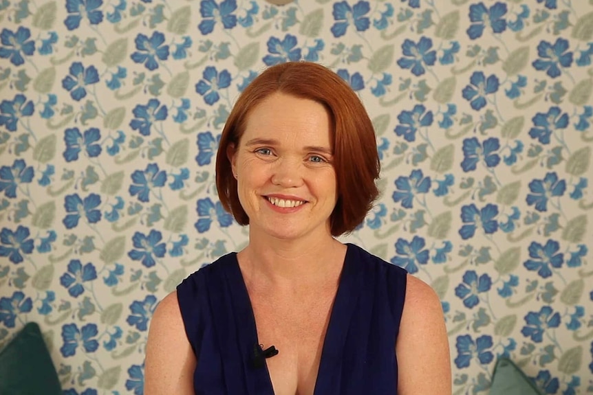 Portrait of a woman with red hair and bright blue eyes.