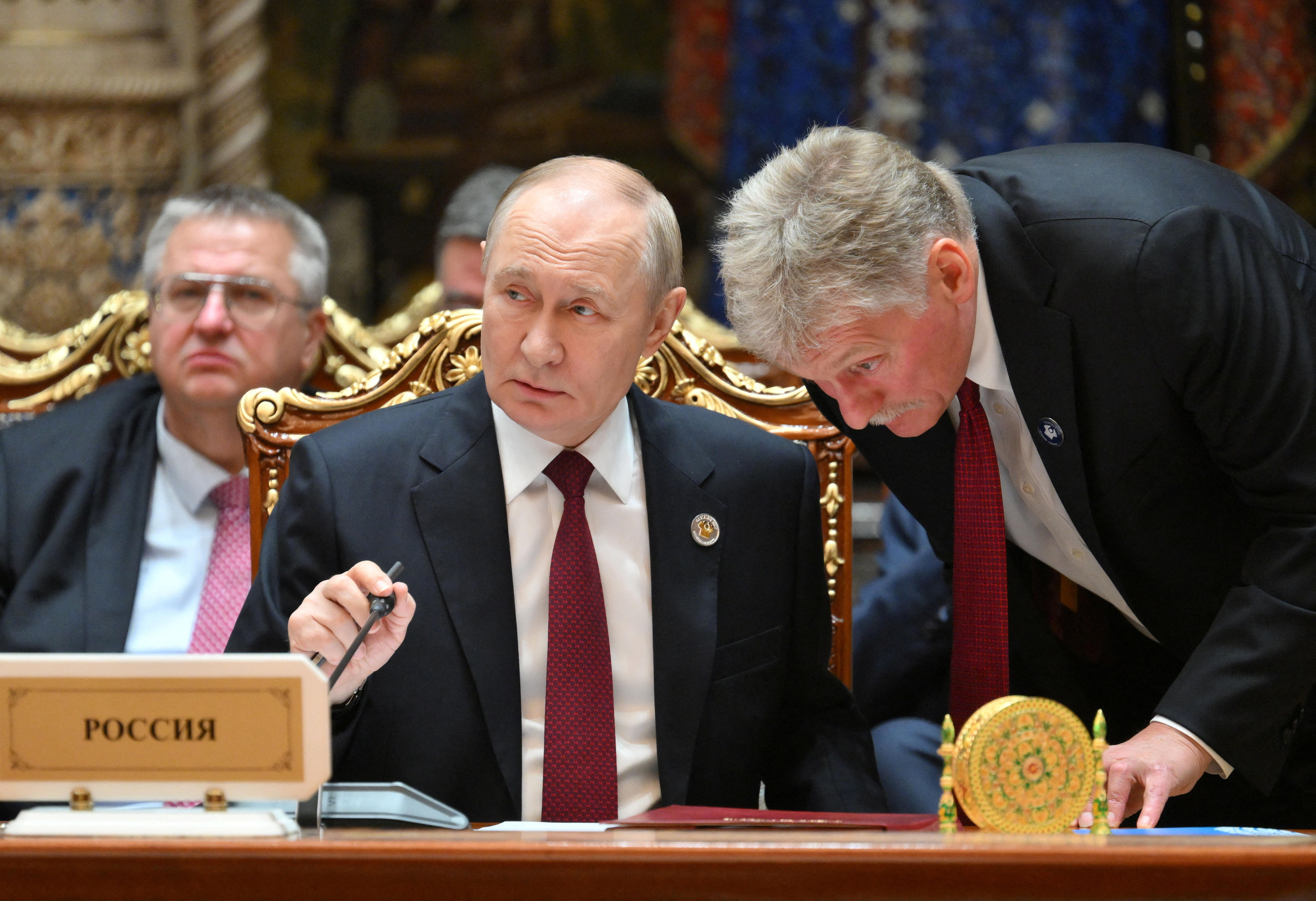 Russian President Vladimir Putin speaks with Kremlin spokesman Dmitry Peskov