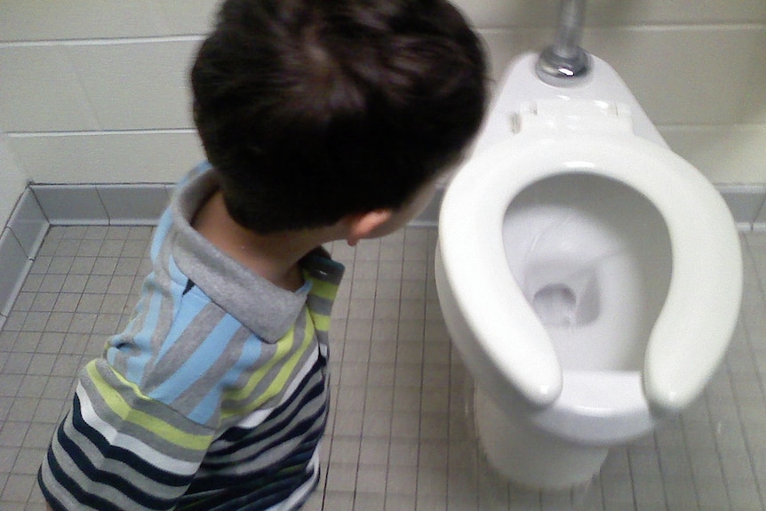 A young boy near a toilet