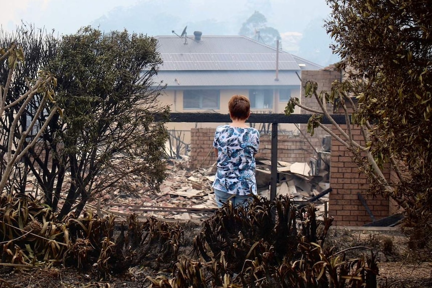 A woman looks at ruins of home