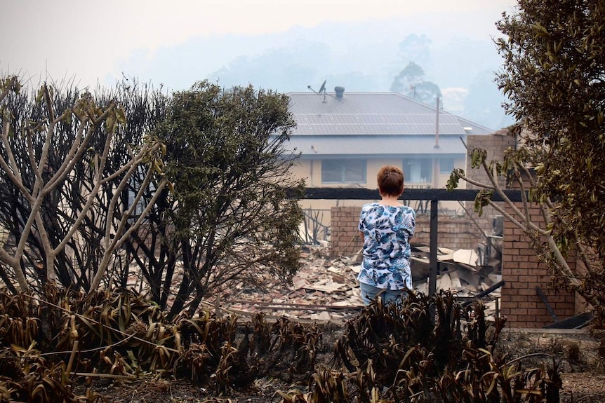 A woman looks at ruins of home