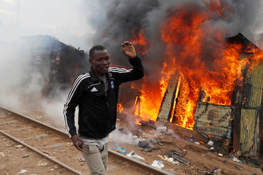 A man runs past a burning shack in a Kenyan slum.