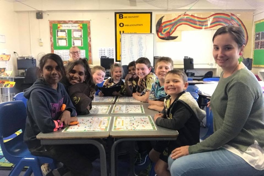 Woman sits at desk in classroom with students