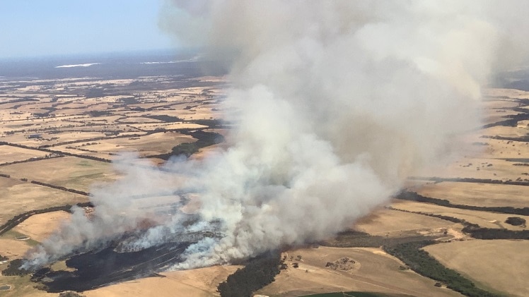A fire is seen burning in crop lands in the distance from an aerial vantage point