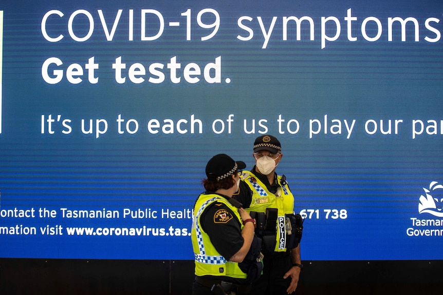 Two police officers under a sign about COVID-19 tests