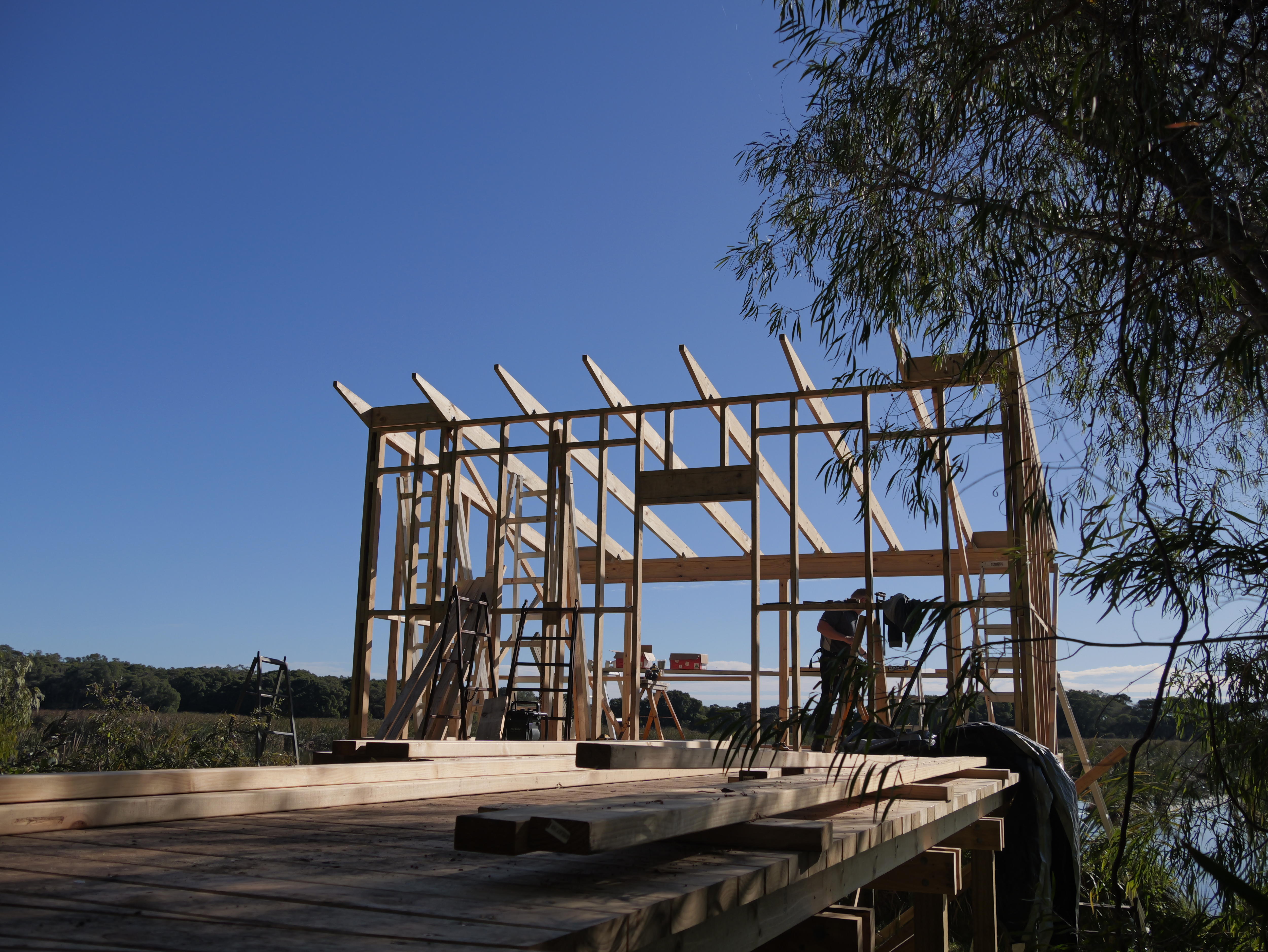 A man stands behind some timber frame.