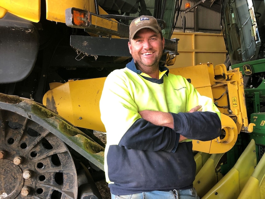 A man standing in front of machinery smiling with his arms crossed