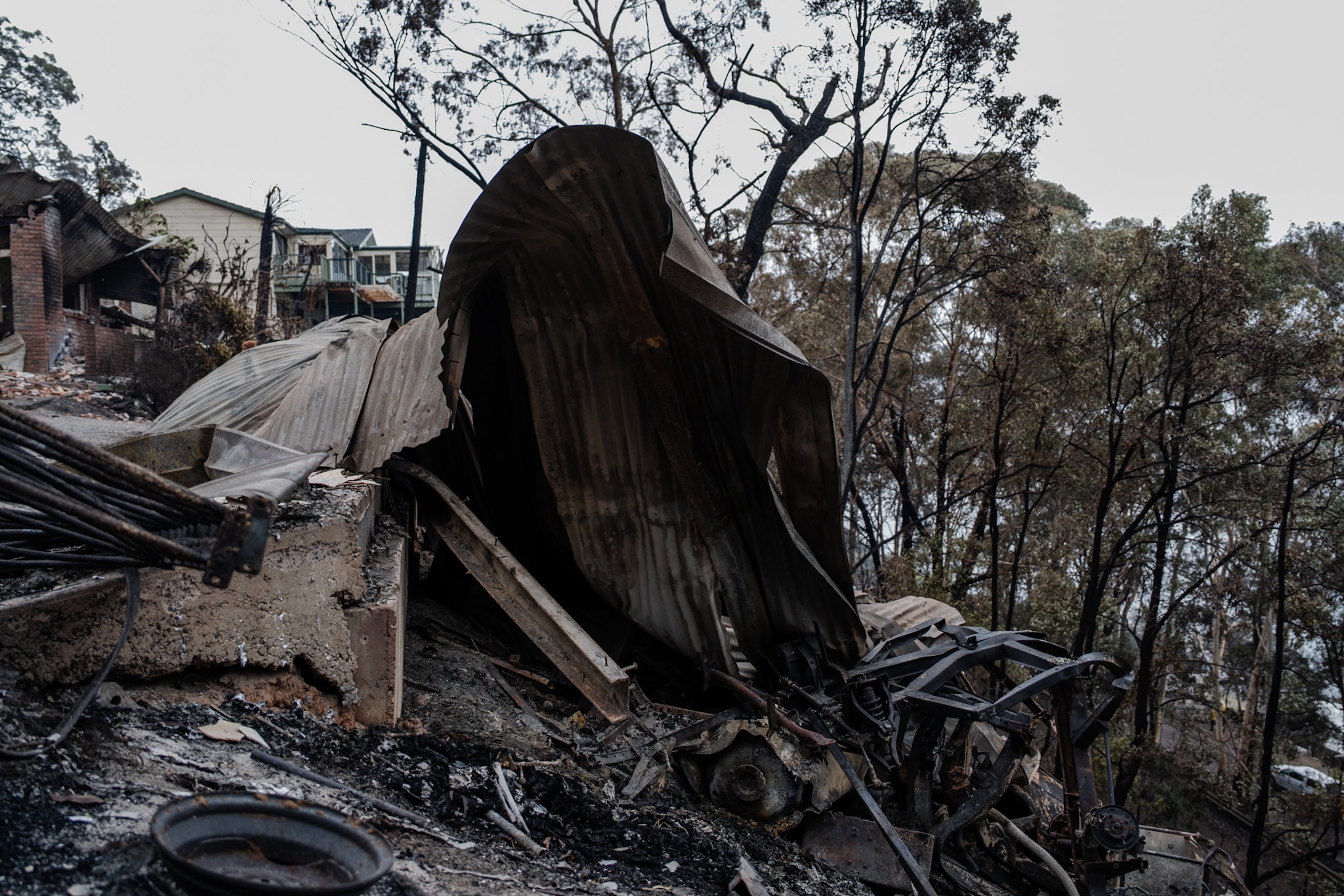 Los restos destruidos de una casa en una zona boscosa tras un incendio.