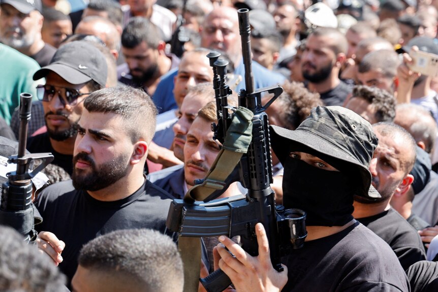 A militant and mourners attend a funeral.