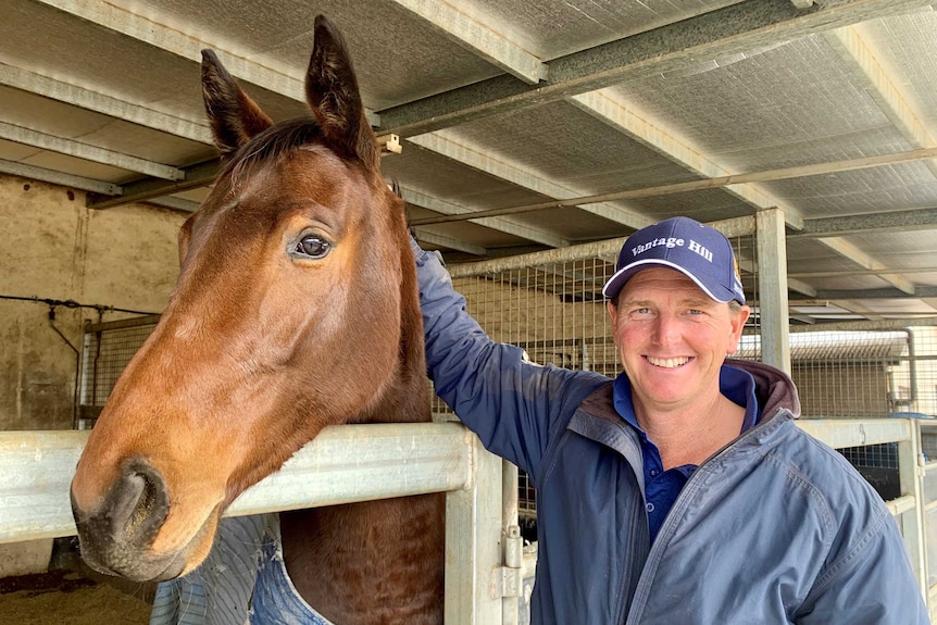 A man with a horse in a stable.