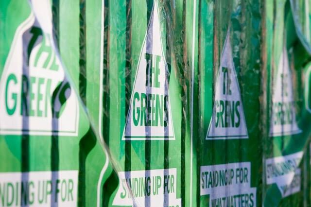 The Greens election posters pinned up along a fence one after the other.