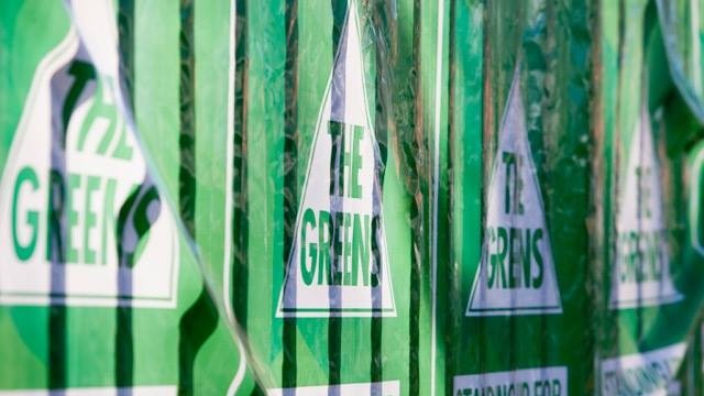 The Greens election posters pinned up along a fence one after the other.