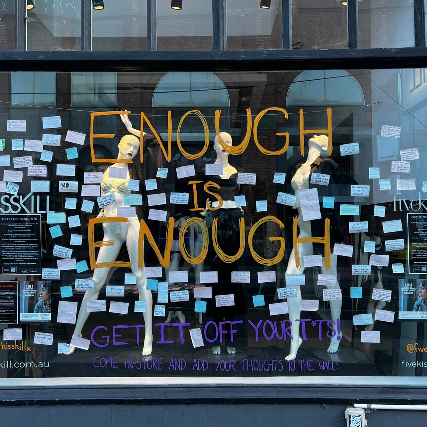 Shop front winder has 'ENOUGH IS ENOUGH' written in orange with lots of post-it notes surrounding it.