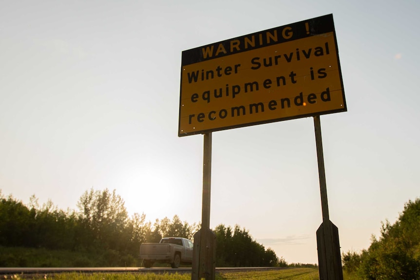 A sign on a road reading "winter survival equipment is recommended'