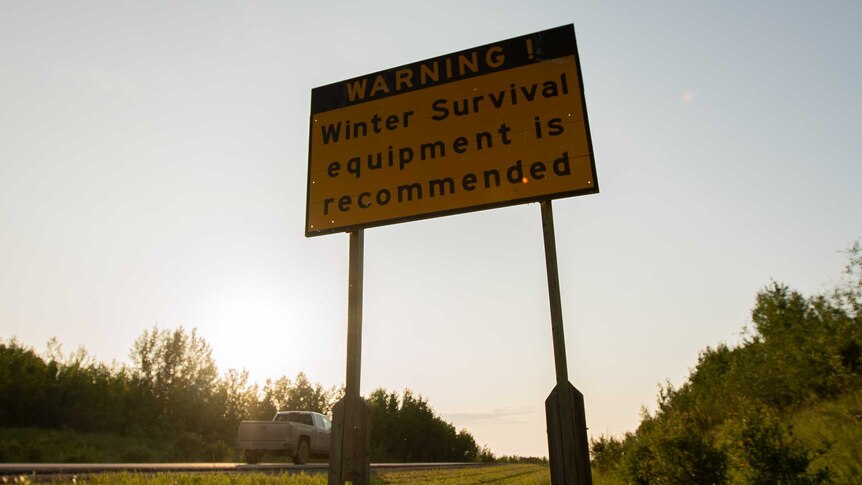 A sign on a road reading "winter survival equipment is recommended'