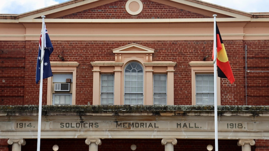 An old building with the Australian flag and Australian Aboriginal flag flying out front.