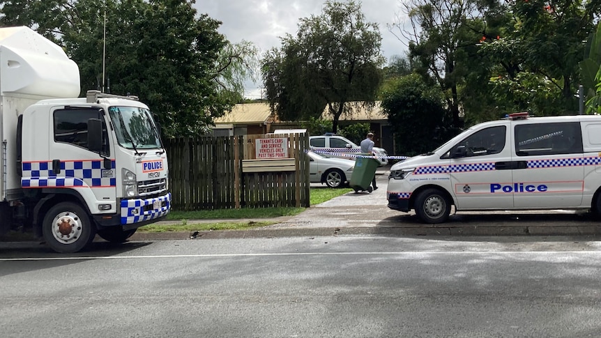 A police truck and van in front of a property cordoned off with police tape.