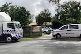 A police truck and van in front of a property cordoned off with police tape.