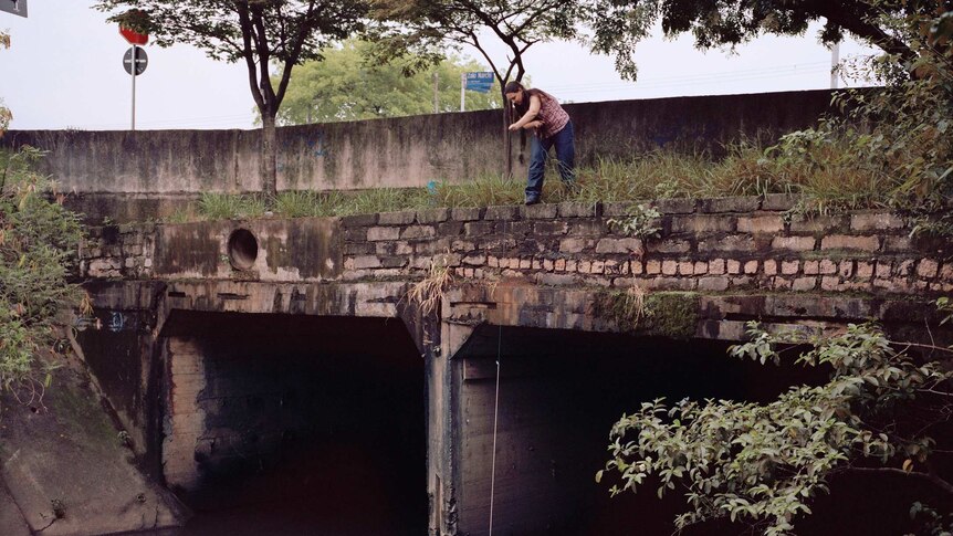 A Sao Paulo resident collects water from the river using a bucket.