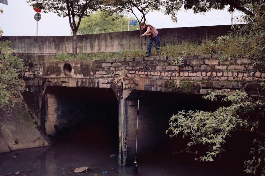 A Sao Paulo resident collects water from the river using a bucket.