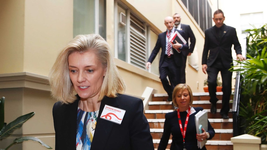 Catherine Brenner walking down some stairs with four people behind her.