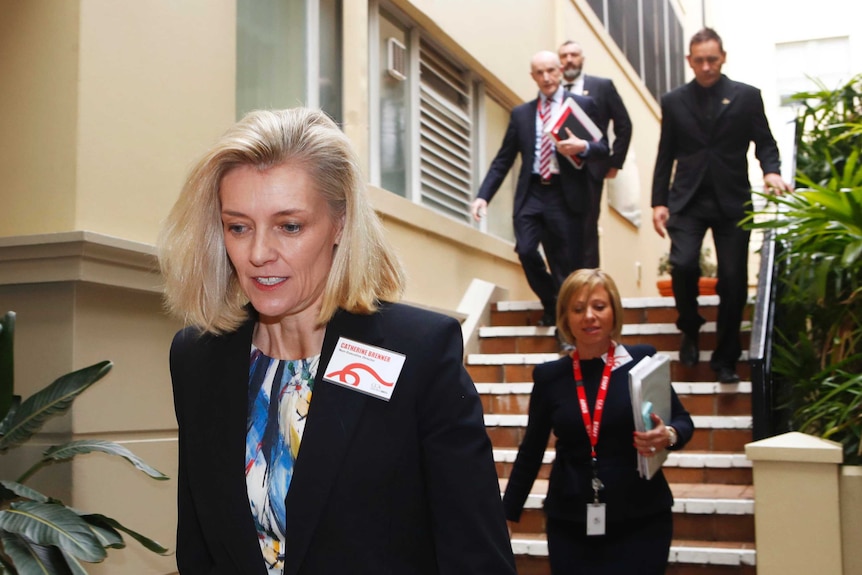 Catherine Brenner walking down some stairs with four people behind her.