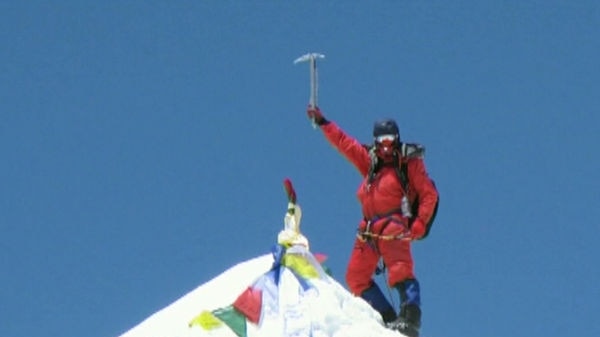 Canberra mountaineer Andrew Lock raises his pick on top of a summit