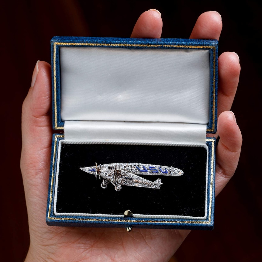 The brooch sits in a case, sparkling silver and blue.