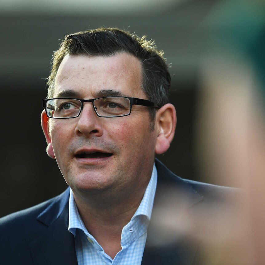 Daniel Andrews speaks to media dressed in a suit and open shirt.