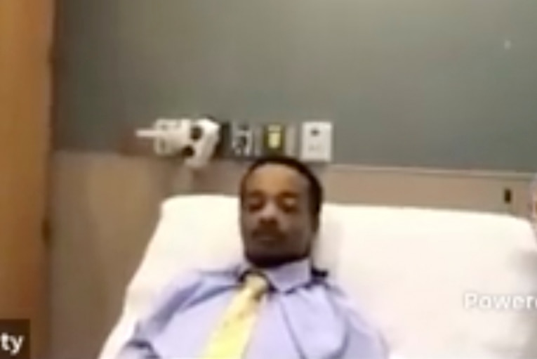 Jacob Blake wears a shirt and tie while he lies in a hospital bed and appears on the Kenosha County Court's video link.
