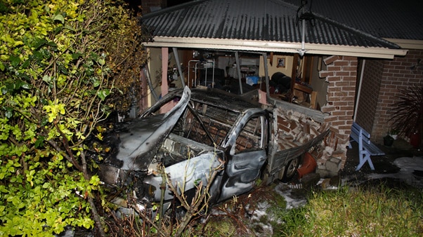 Burnt out car in front of a house in Glenorchy