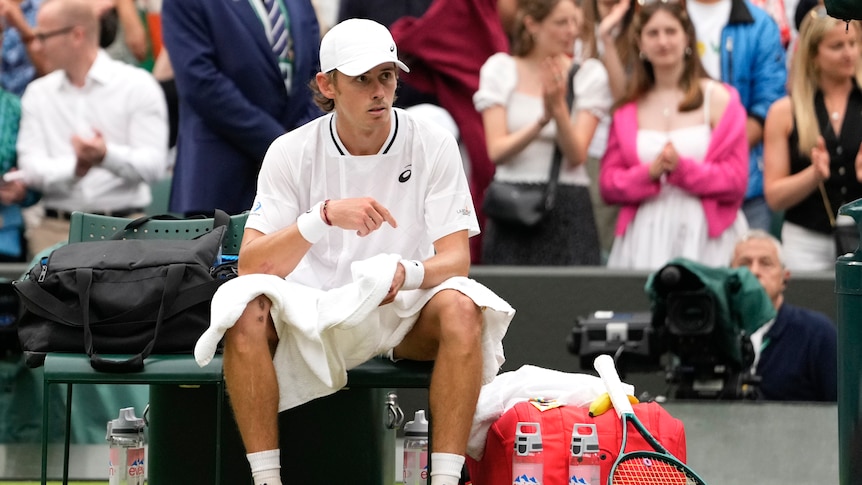 Australia's Alex de Minaur sits on his seat showing no emotion after winning a match at Wimbledon.