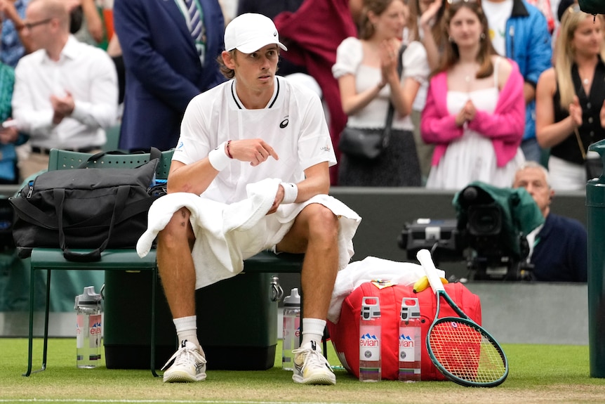 Australia's Alex de Minaur sits on his seat showing no emotion after winning a match at Wimbledon.