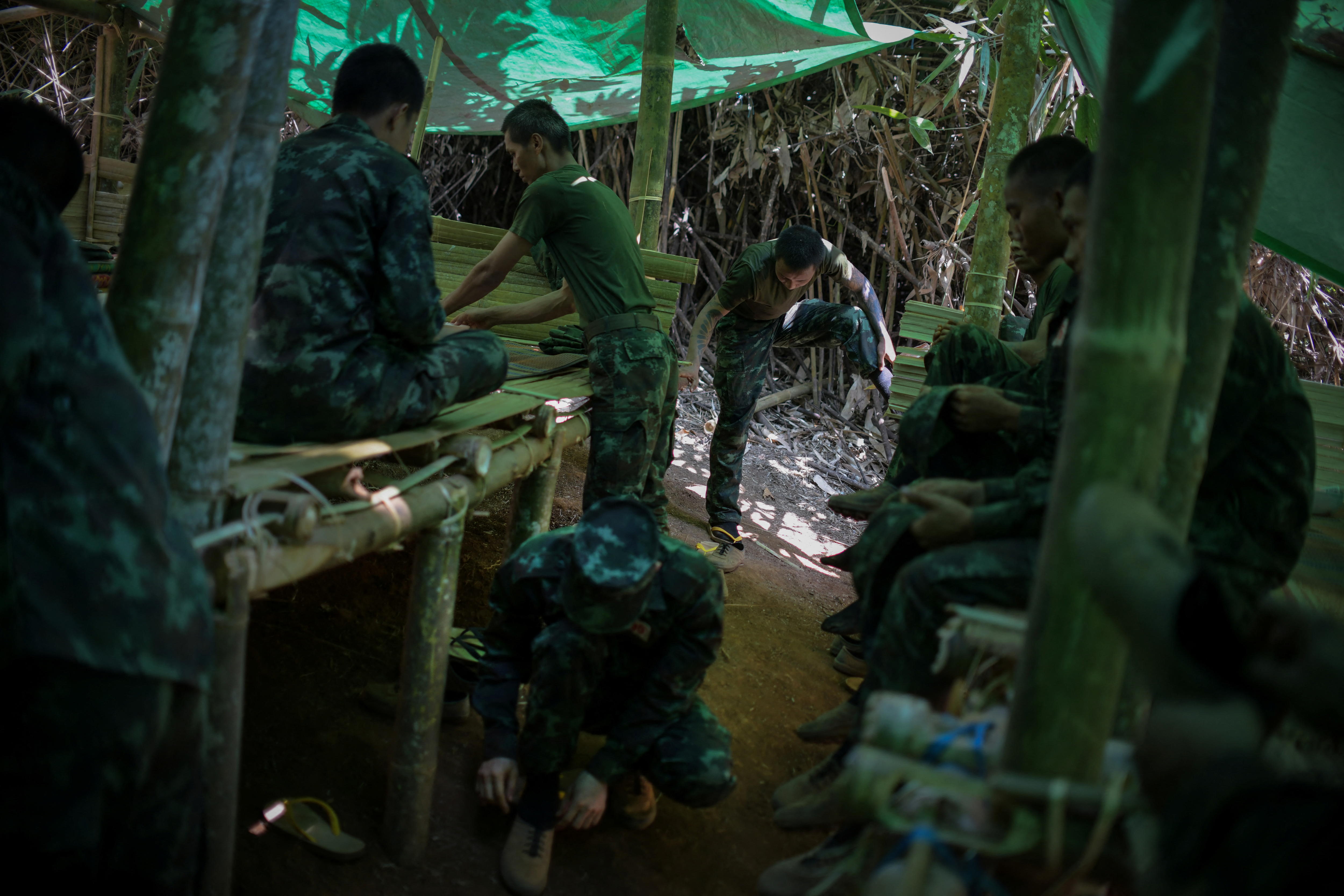 Men in camo work on a table in the jungle. 