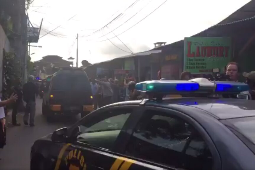 Bali police vehicles drive down the street.