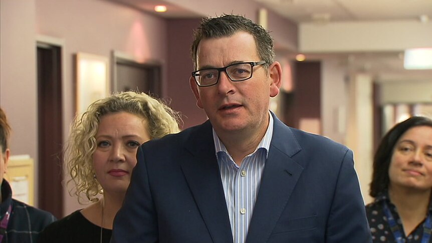 Daniel Andrews and Jill Hennessy hold a press conference in a hospital corridor.