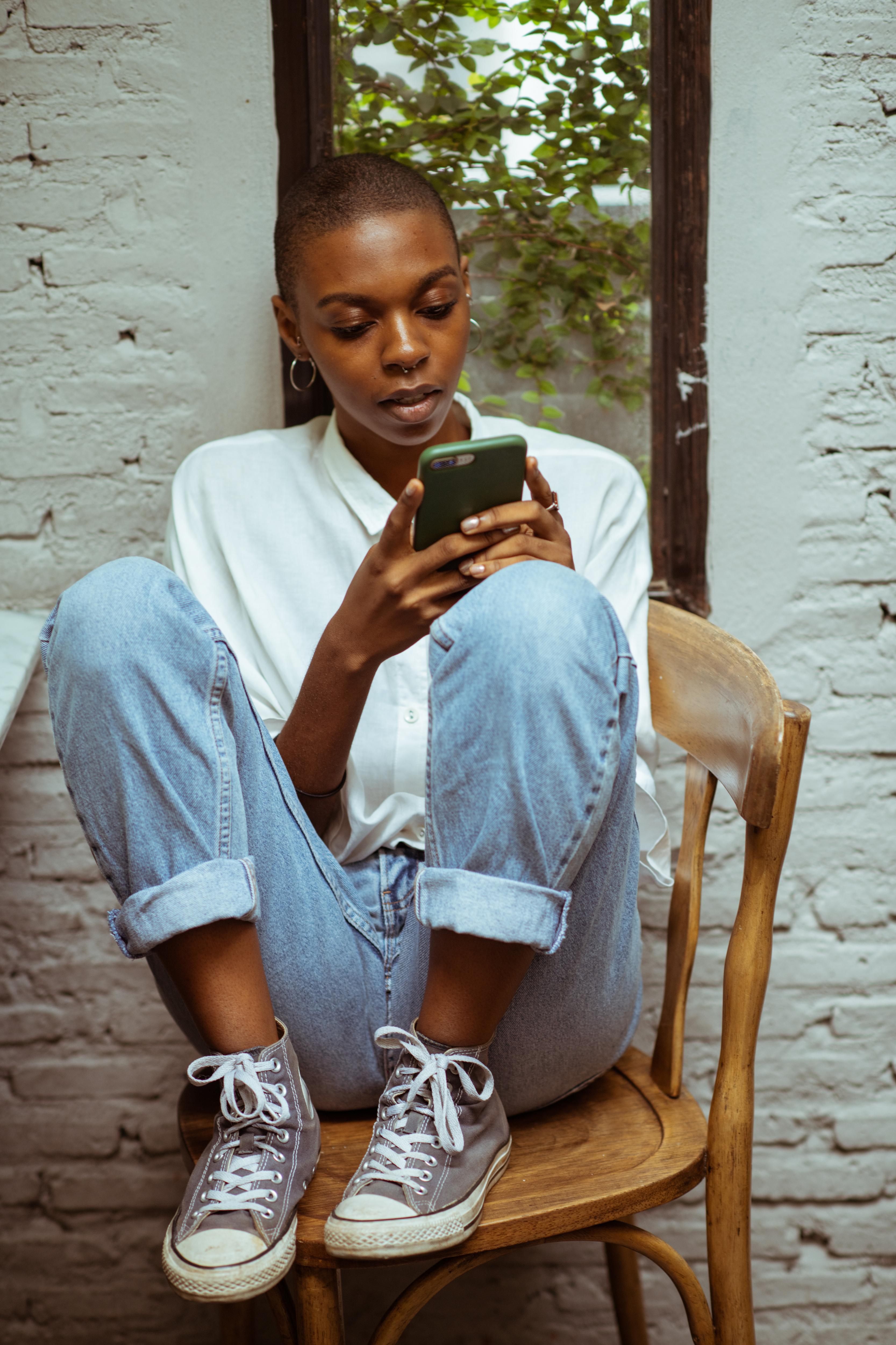 Woman sits on chair looking at her phone