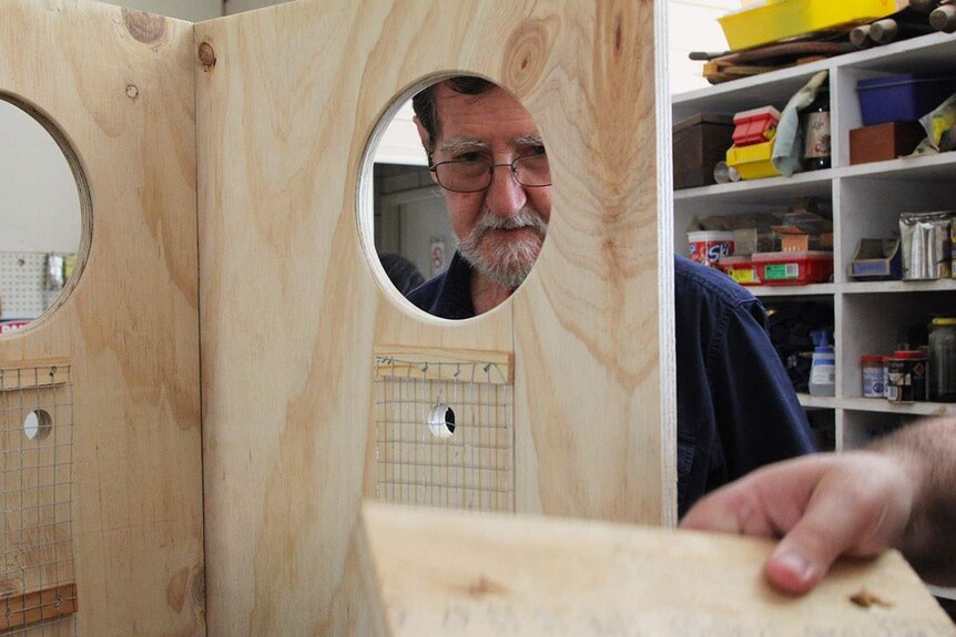 A man looking through a box with a hole in it