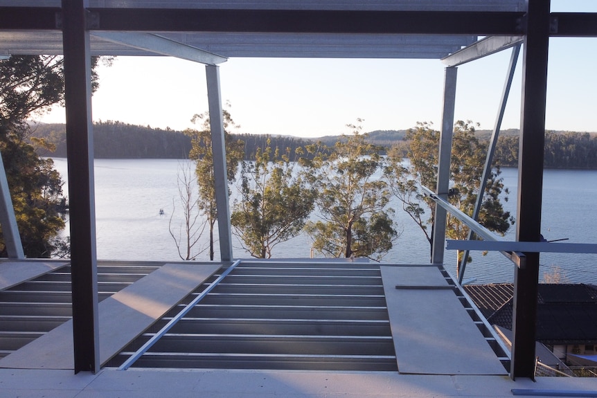 Views over a large lake from the inside of a house with huge windows.