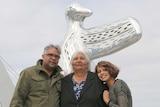 Laurel Nannup stands with her son Brett and granddaughter Lily Wilson in front of a sculpture of a silver bird.