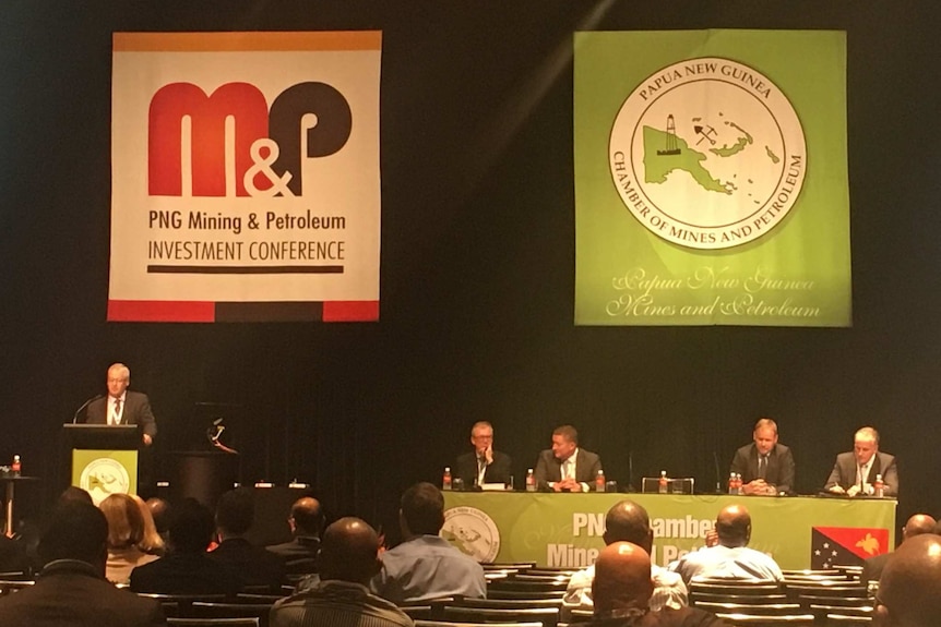 A wide view of a speaker on stage addresses the conference audience.