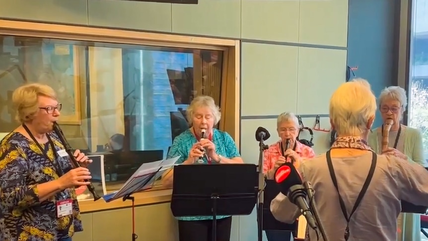 Women sit together playing recorders.