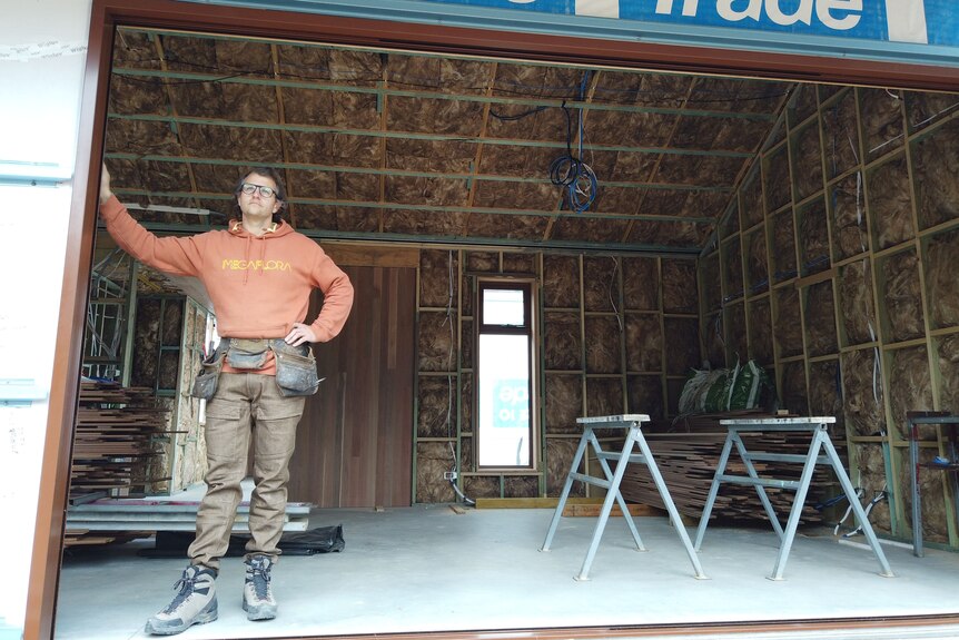 Homme debout à l'intérieur du cadre d'une maison en construction. 