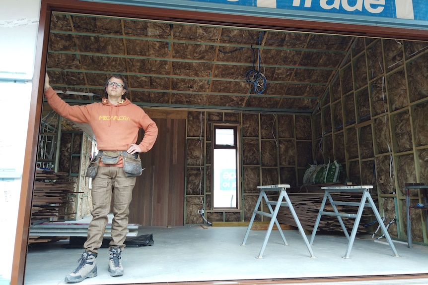 Man standing inside the frame of a house being constructed. 