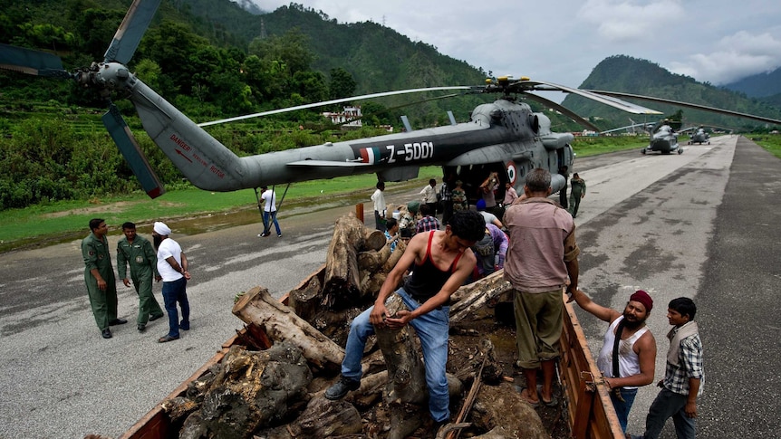 Indian workers offload wood for the cremation of flood victims