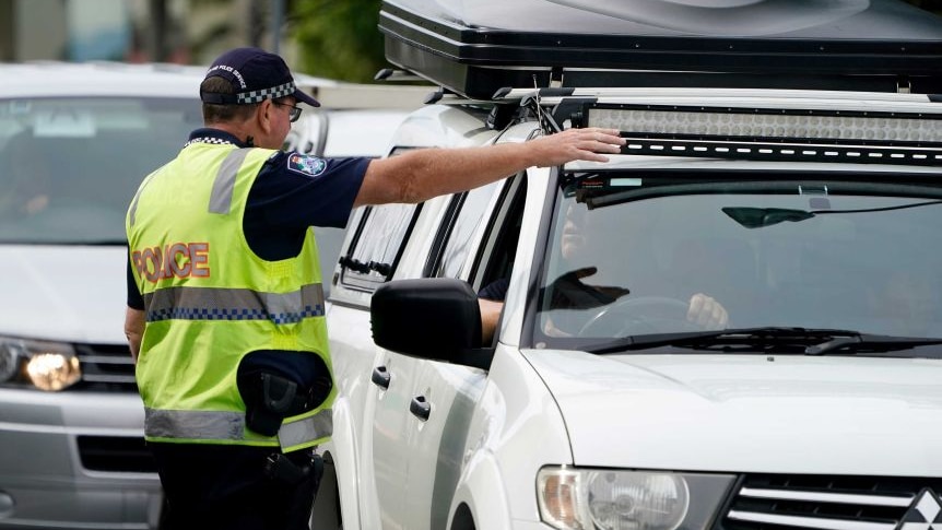 Queensland police officer directs motorists at a border checkpoint on the Queensland-NSW border.