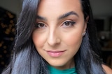 Young woman wearing green shirt smiles at camera.